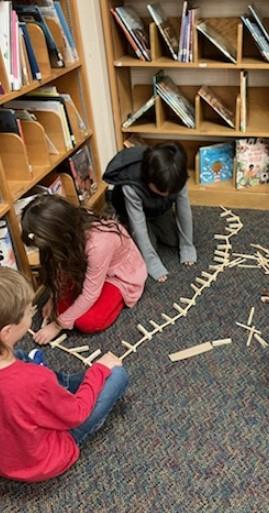 Students building fence with popsicle sticks and clothespins